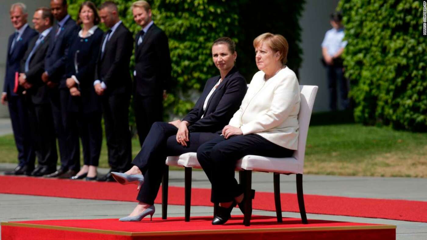 Angela Merkel pictured seated during the national anthem, following a series of public "shaking attacks".