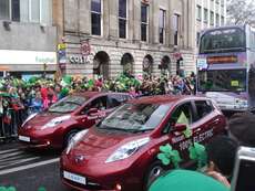 Seltsame Teilnehmer an der Parade: Werbung für Autos und ein Bus voll mit Touristen