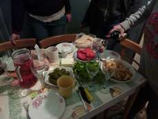 Reich gedeckter Tisch mit eingelegten Paprika und Gurken, Salzkäse, Lawasch, Pfirsichkompott und frischem Koriander