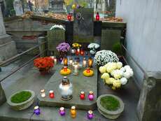 Ein mit vielen bunten Kerzen und Blumen geschmücktes Grab.